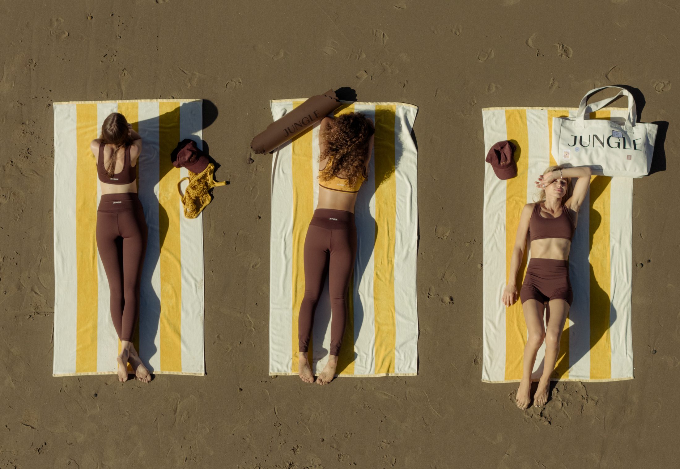 Three figures in Jungle apparel on striped beach towels